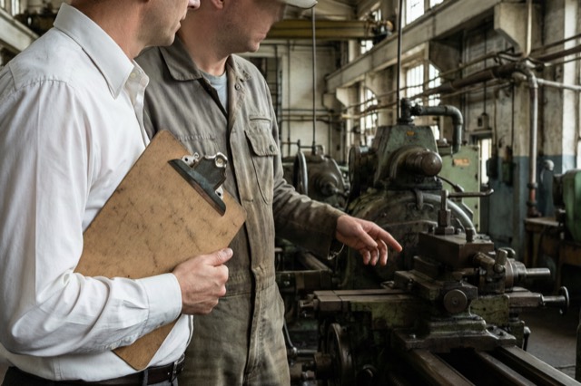 A manager and an engineer talking on a factory floor